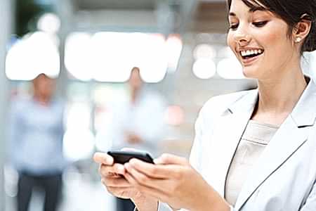 Pretty happy executive reading SMS on blur background Güzel Kadın Mesaj Okumakta